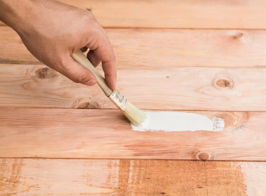 Man painting wooden floor in white color with a brush