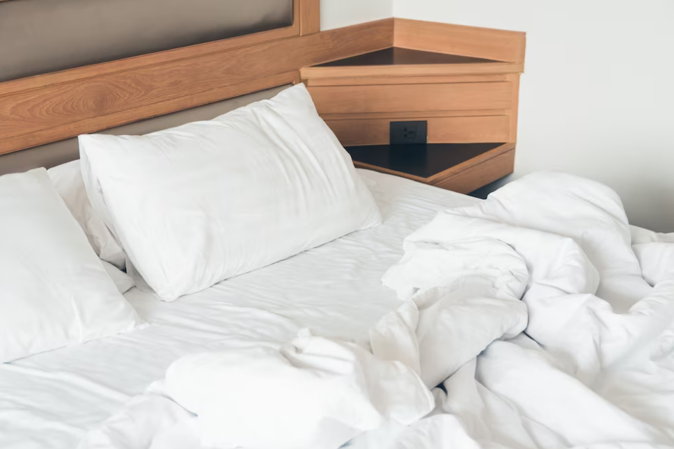 white bedclothes on a wooden bed with pillows and a blanket