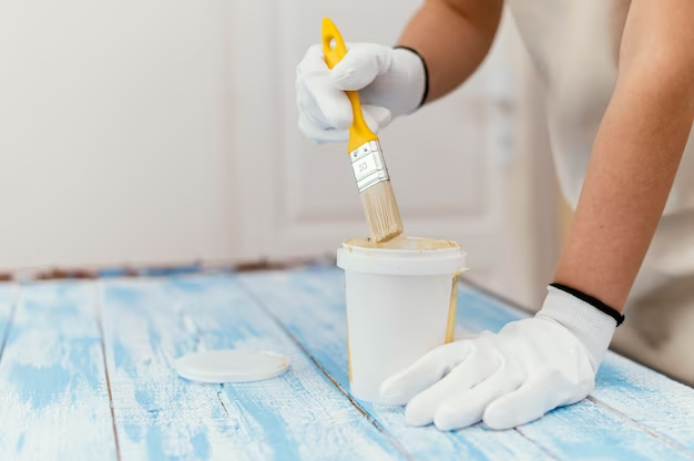 Man painting a table in white gloves