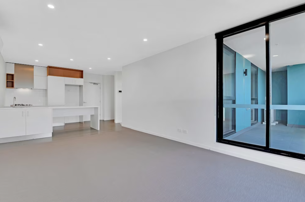bright room with black window, gray floor, and white kitchen wall